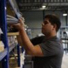 Medewerker van Lintzaagmeesters pakt opgerolde zaagbanden uit het magazijnrek